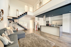 Een modern interieur met een trap, een keuken en een woonruimte met een bank en vloerkleed.