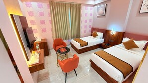 Une chambre d’hôtel avec deux lits, un bureau, une chaise, une télévision et un ventilateur de plafond.