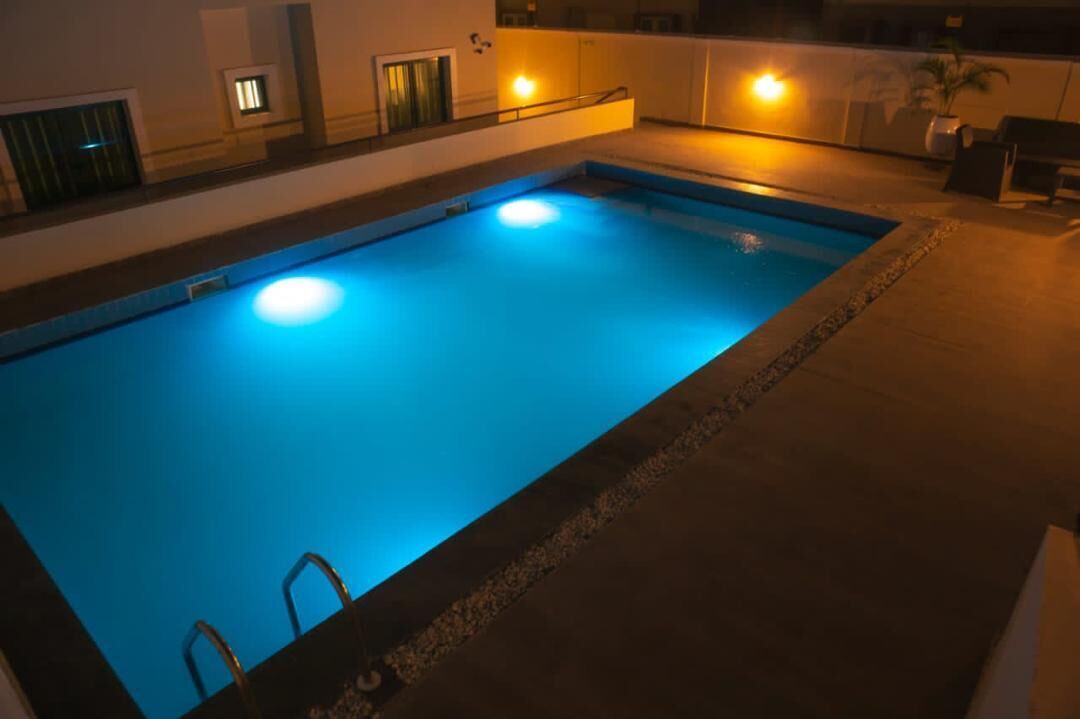 Ein Pool mit Fliesen umgeben und einer kleinen Treppe zum Wasser.