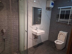 A bathroom with a glass shower enclosure, a sink with a mirror, and a toilet. - Sun Heaven Residence Lekki (Lekki)