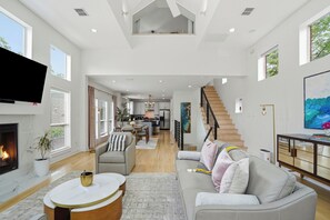 A spacious living area with a fireplace, a dining area, and a kitchen in the background.