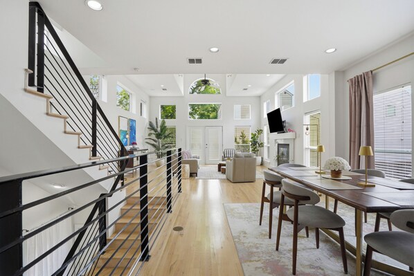 Un amplio salón con una escalera, una mesa de comedor y una chimenea.