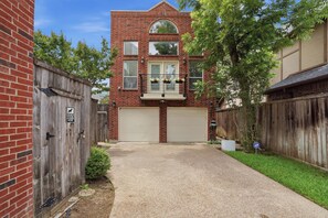 A two-story brick building with a central entrance, a covered porch, and a small garden area.