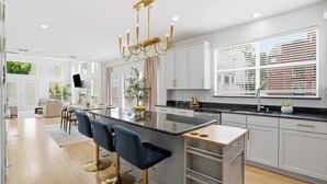 Une cuisine moderne dotée d’un îlot central, de tabourets de bar et d’un lustre.
