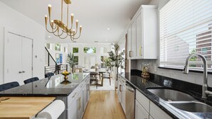 Une cuisine moderne dotée d’un îlot central, d’appareils électroménagers en acier inoxydable et d’un lustre.