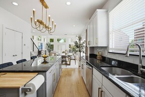 Una cocina moderna con una isla central, electrodomésticos de acero inoxidable y una araña.