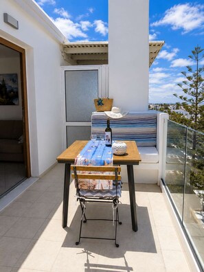 A balcony with a table, a chair, a bottle, and a basket. - Island Flavor - Naxos Seaview Retreat With Balcony (Naxos)