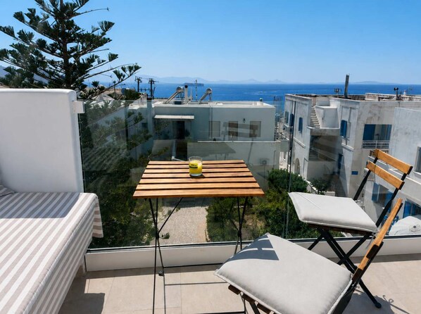 A balcony with a table, chairs, and a glass barrier. - Island Flavor - Naxos Seaview Retreat With Balcony (Naxos)