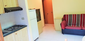 Eine kleine Küche mit einem Gaskochfeld, einem weißen Kühlschrank und einem Holzschrank.