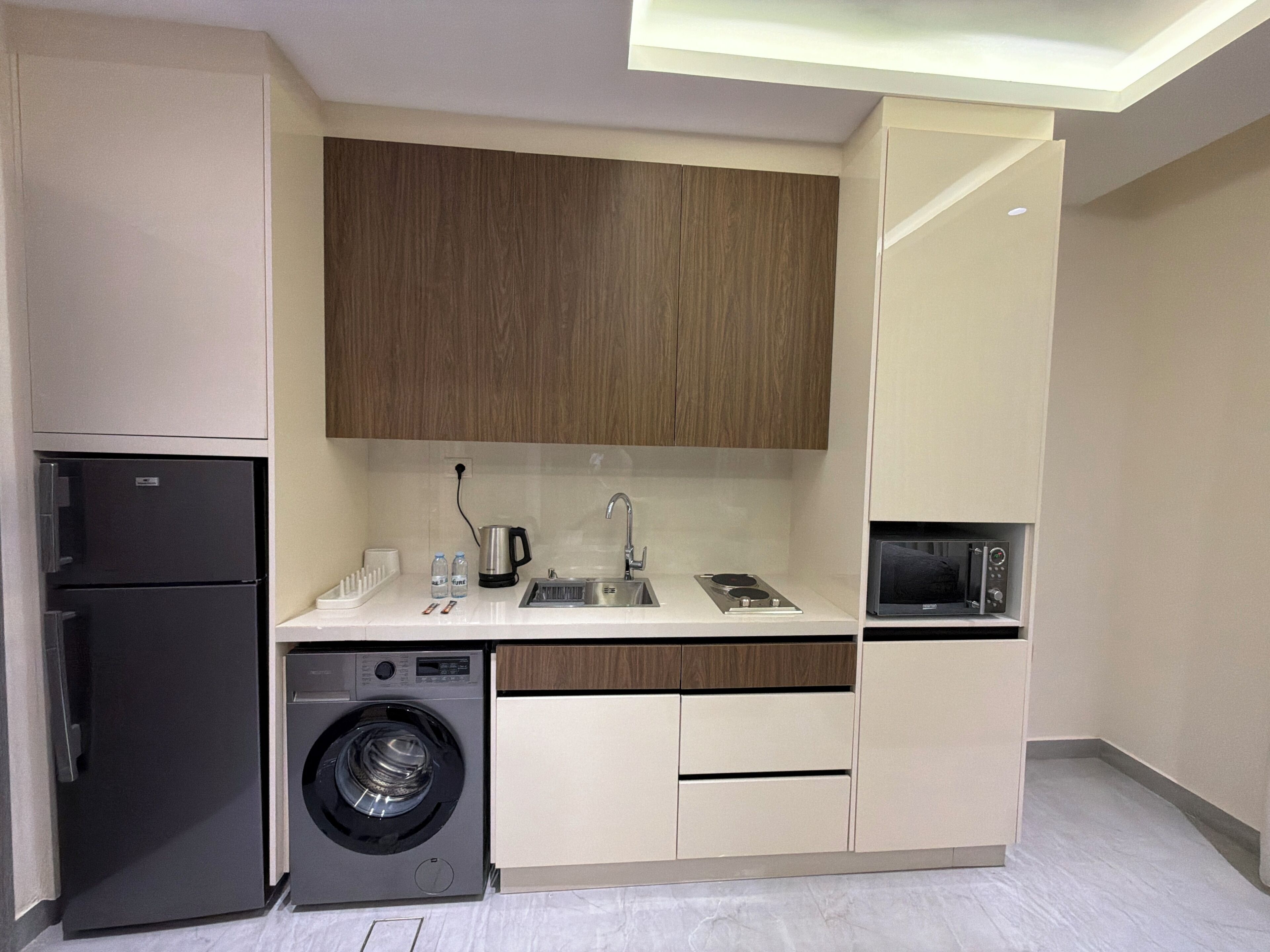 Cocina compacta con lavadora, cafetera y microondas.