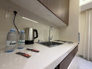 A modern kitchen with a stainless steel sink, a kettle, and bottled water. - 204 JRE Apartment With Stunning Boulevard Veiw (Amman)