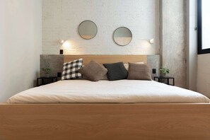 Ein Bett mit hölzernem Kopfteil, zwei runden Spiegeln und vielen Kissen.