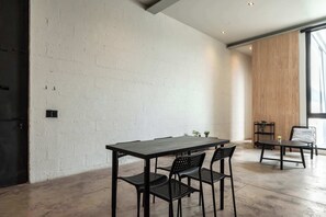 Ein modernes Interieur mit Backsteinwand, Holzpaneel, Tisch mit Stühlen und Fenster.
