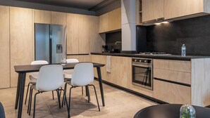 Une cuisine moderne avec des meubles en bois, une table à manger avec des chaises et un four encastré.