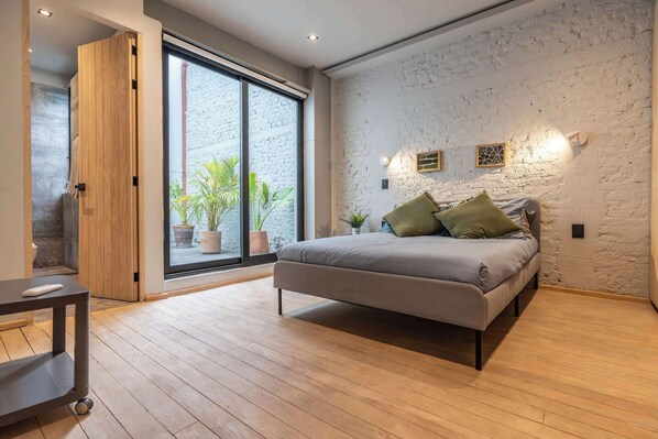 Ein Schlafzimmer mit einem Bett, Holzboden, einer Schiebetür und einer weißen Ziegelwand.