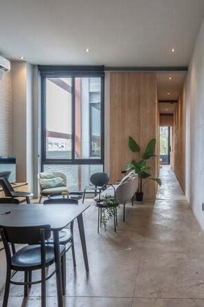 Ein modernes Interieur mit Essbereich, großen Fenstern und einem Flur, der zu einem weiteren Raum führt.