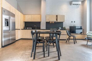 Een moderne keuken met houten kastjes, een roestvrijstalen koelkast, een eettafel met stoelen en een flatscreentelevisie.