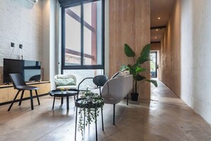 Een moderne woonkamer met een televisie, zitmeubels en een groot raam.