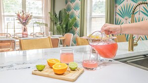 Eine Küchenarbeitsplatte mit Schneidebrett, Zitrusfrüchten und Gläsern mit rosa Getränk.