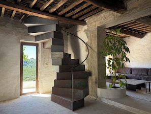 Eine Wendeltreppe in einem rustikalen Raum mit einer Betonwand, einem Blumentopf und einem Sofa.