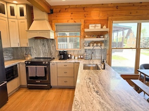 A kitchen with a stove, oven, sink, and marble countertop.
