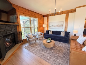 A cozy living room with a fireplace, a dark blue sofa, a round coffee table, and a stone fireplace.