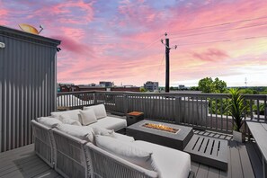A rooftop deck with a white outdoor sofa, a fire pit, and a view of the city skyline. - Luxury 2BR Condo on Peters St - Walk to FIFA & Mercedes-Benz Stadium (Atlanta)