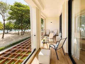 Un balcon avec vue sur la plage, un coin salon avec des chaises et une table, et un plancher en bois.