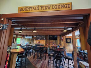 Ein Restaurant mit Holzeinrichtung, Tischen und Stühlen, und einem Schild mit der Aufschrift 'Mountain View Lounge'.