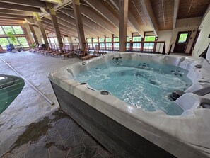 Ein Whirlpool mit Steinboden, Holzbalken und Blick ins Freie.