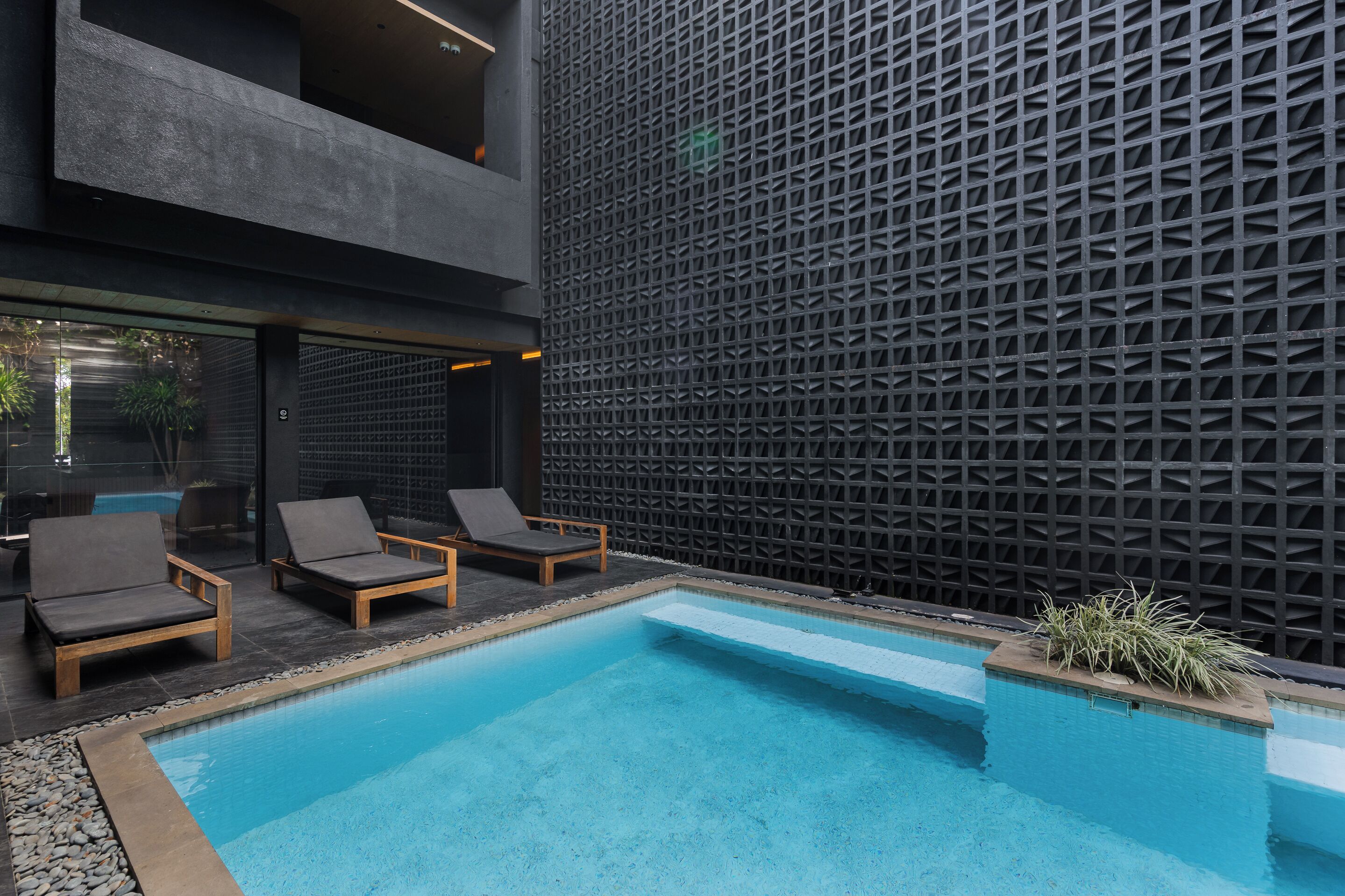 A modern pool area with lounge chairs and a geometric wall.