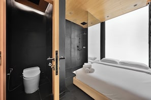 A modern hotel room with a large bed, a shower area, and a view through a window.