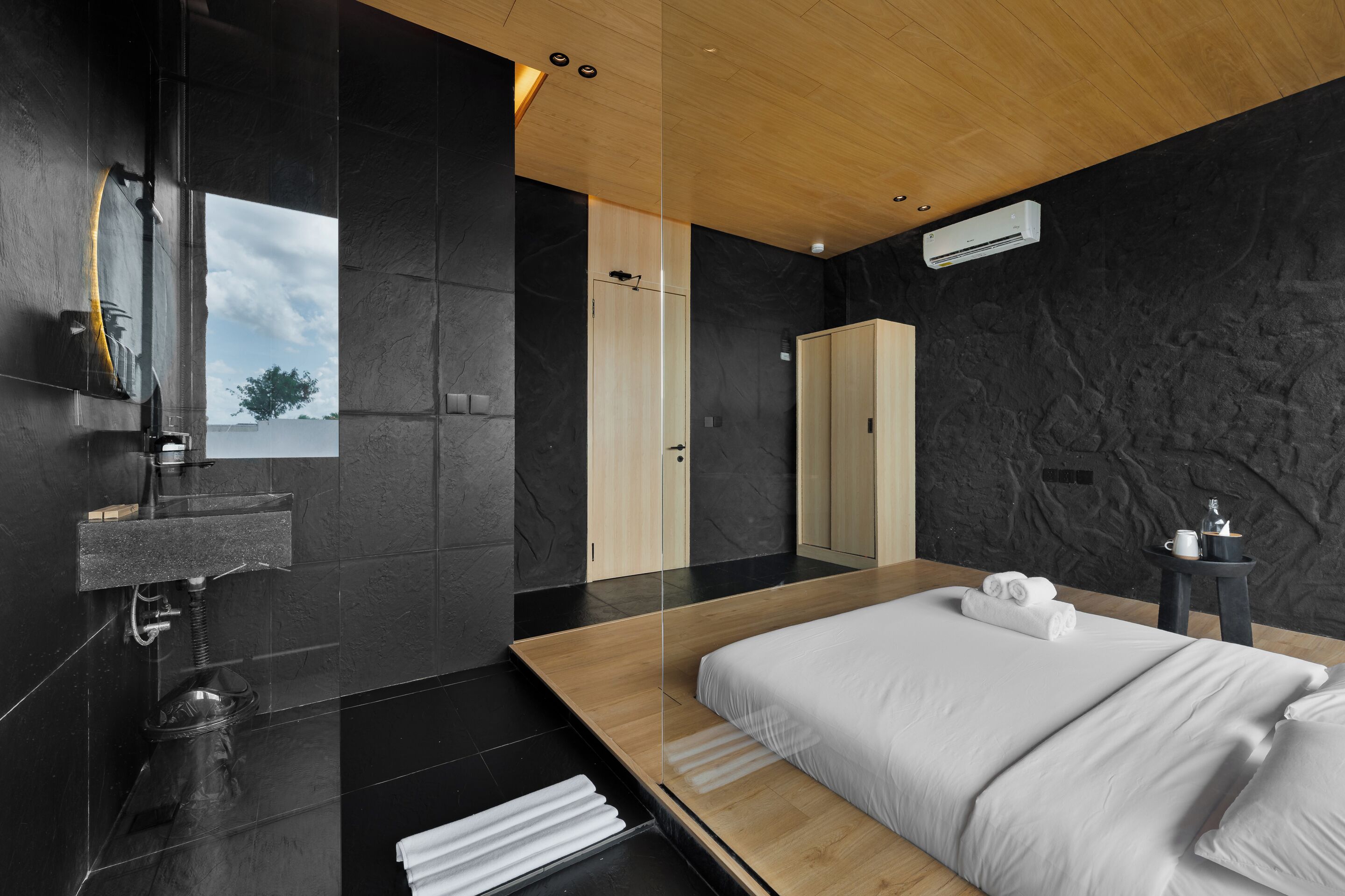 A modern bedroom with a wooden bed, a built-in sink, and a large mirror.