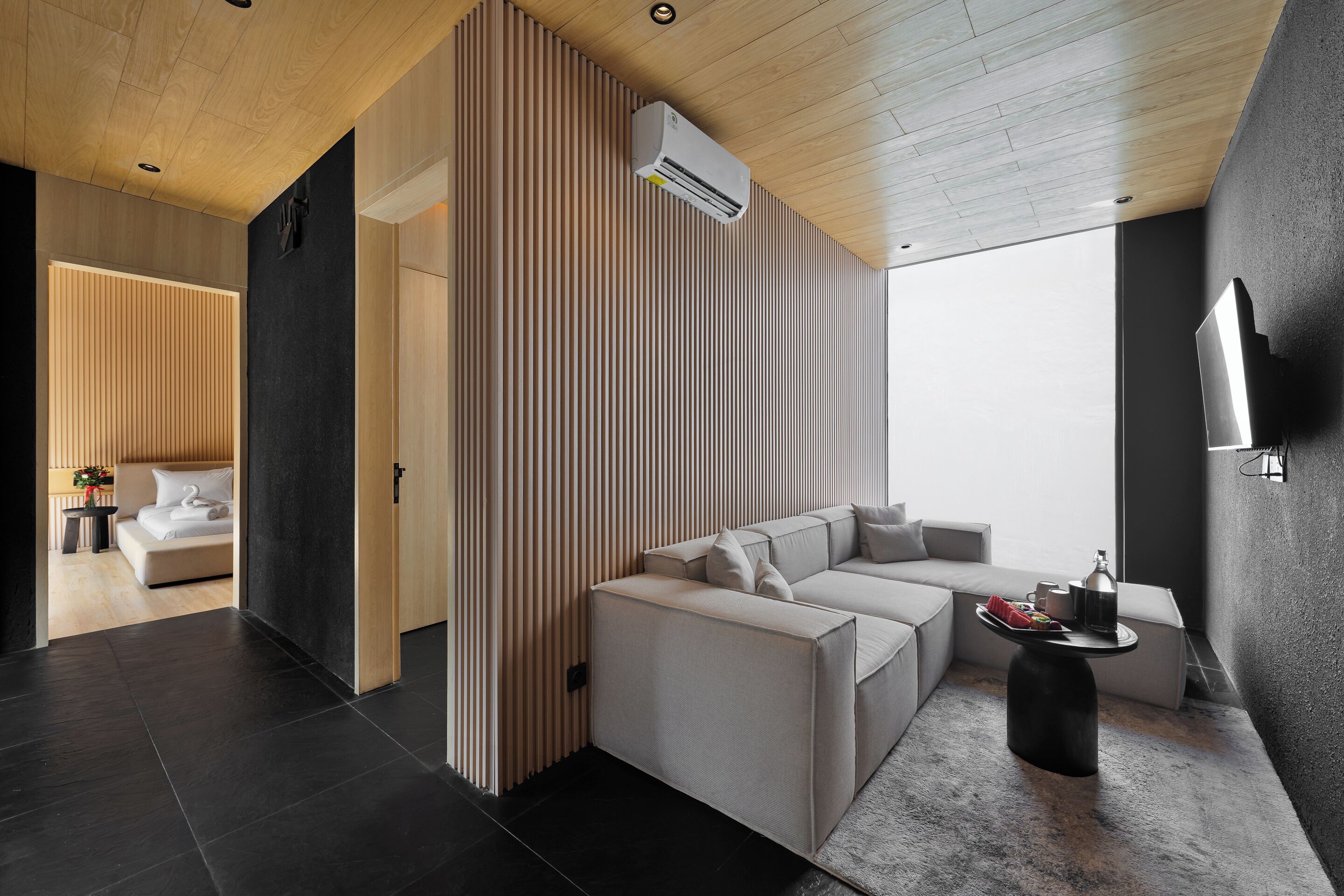 A modern living room with a sectional sofa, a coffee table, and a TV mounted on the wall.