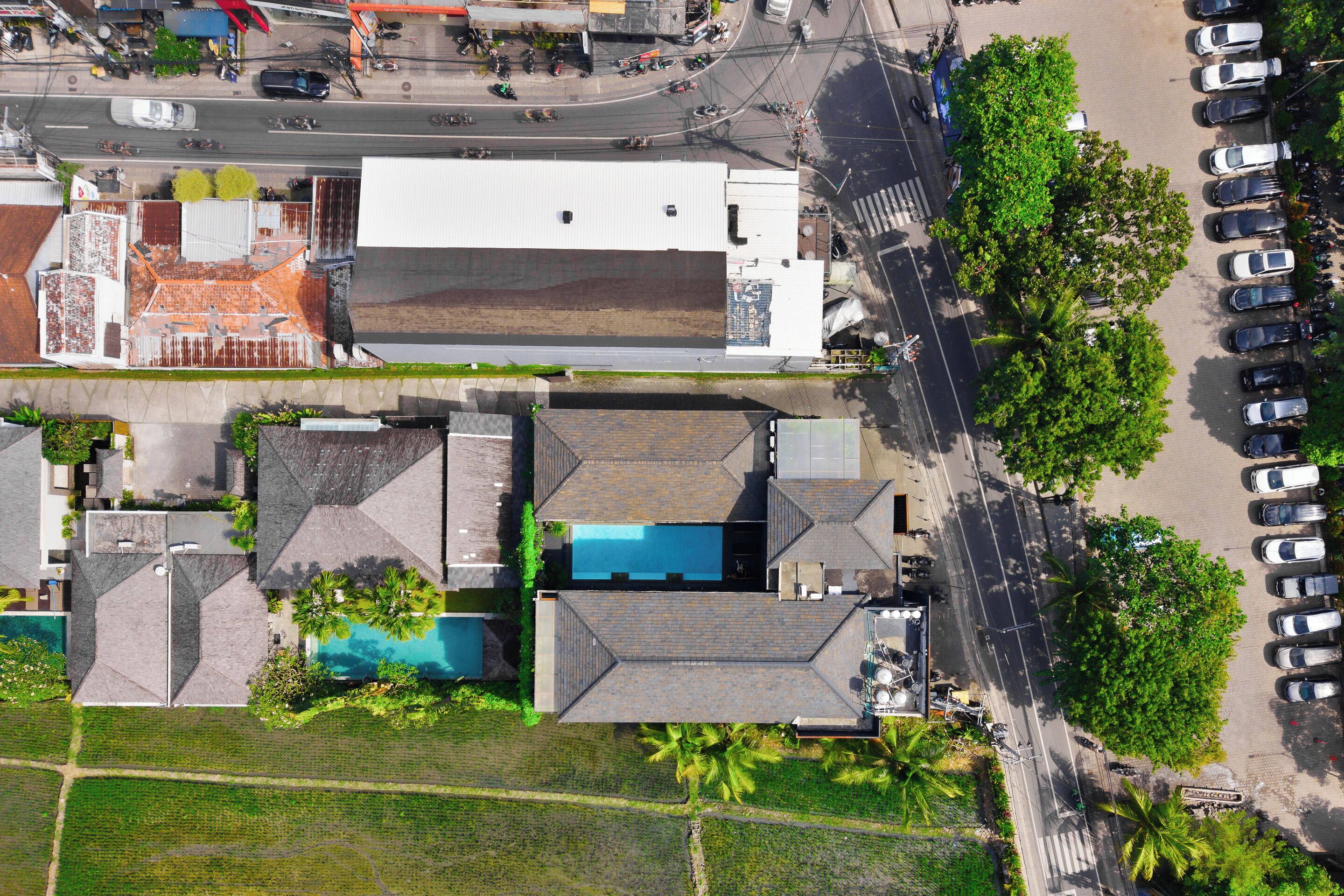 Ett flygbildsfoto av ett bostadsområde med en stor byggnad, en swimmingpool och en parkeringsplats.