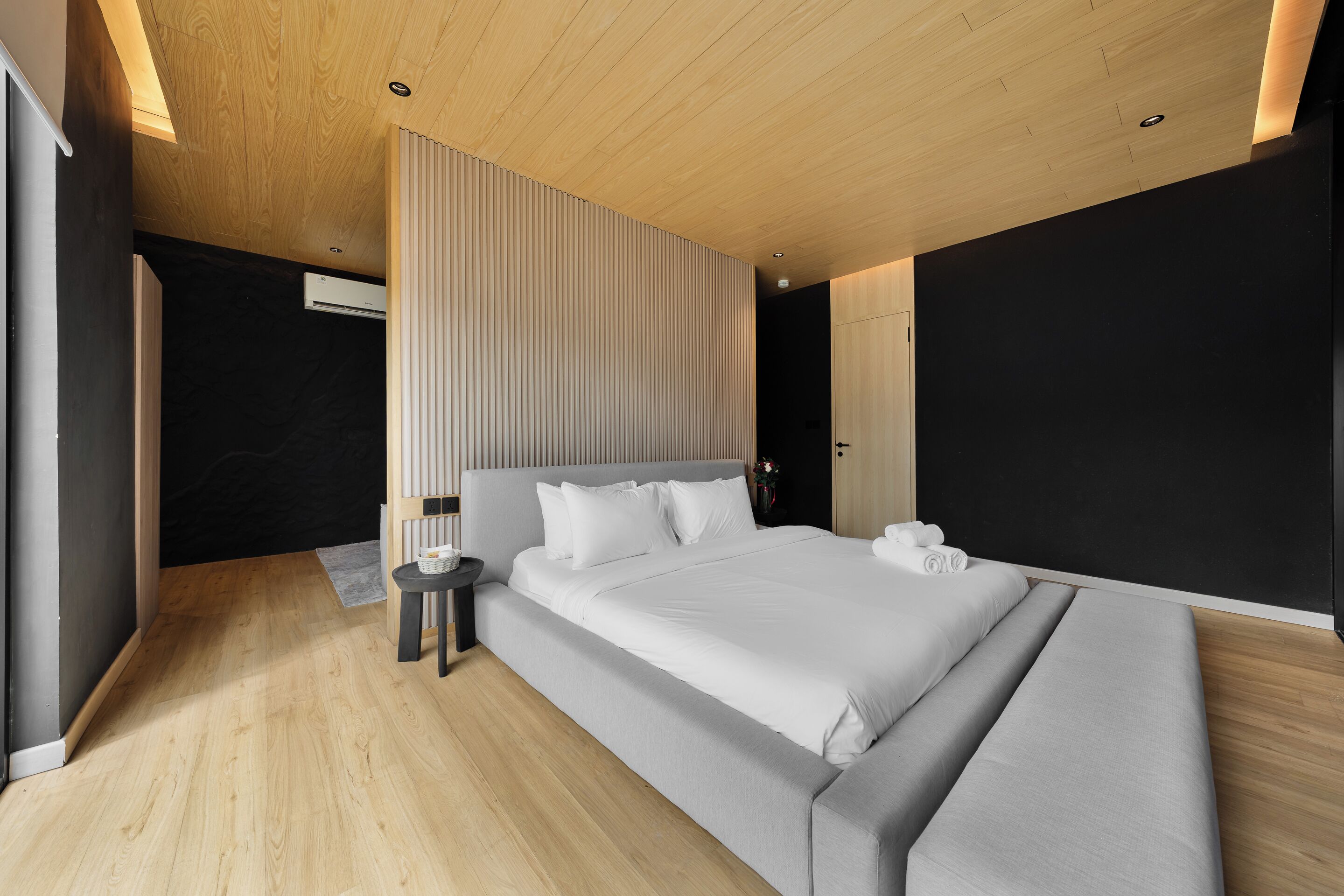 Ein modernes Schlafzimmer mit einem großen Bett, einem Nachttisch und einer wandmontierten Klimaanlage.