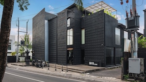 Un edificio moderno con fachada negra, una entrada visible y un letrero que dice 'M4YA BERHANWA'.