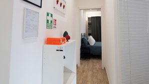 A hallway with a bed, a white cabinet, and a door with blinds. - Partesia  (Naples)