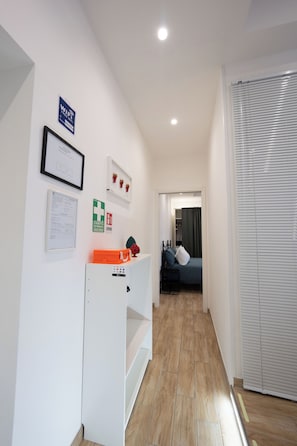 A hallway with a bed, a white cabinet, and a door with blinds. - Partesia (Naples)