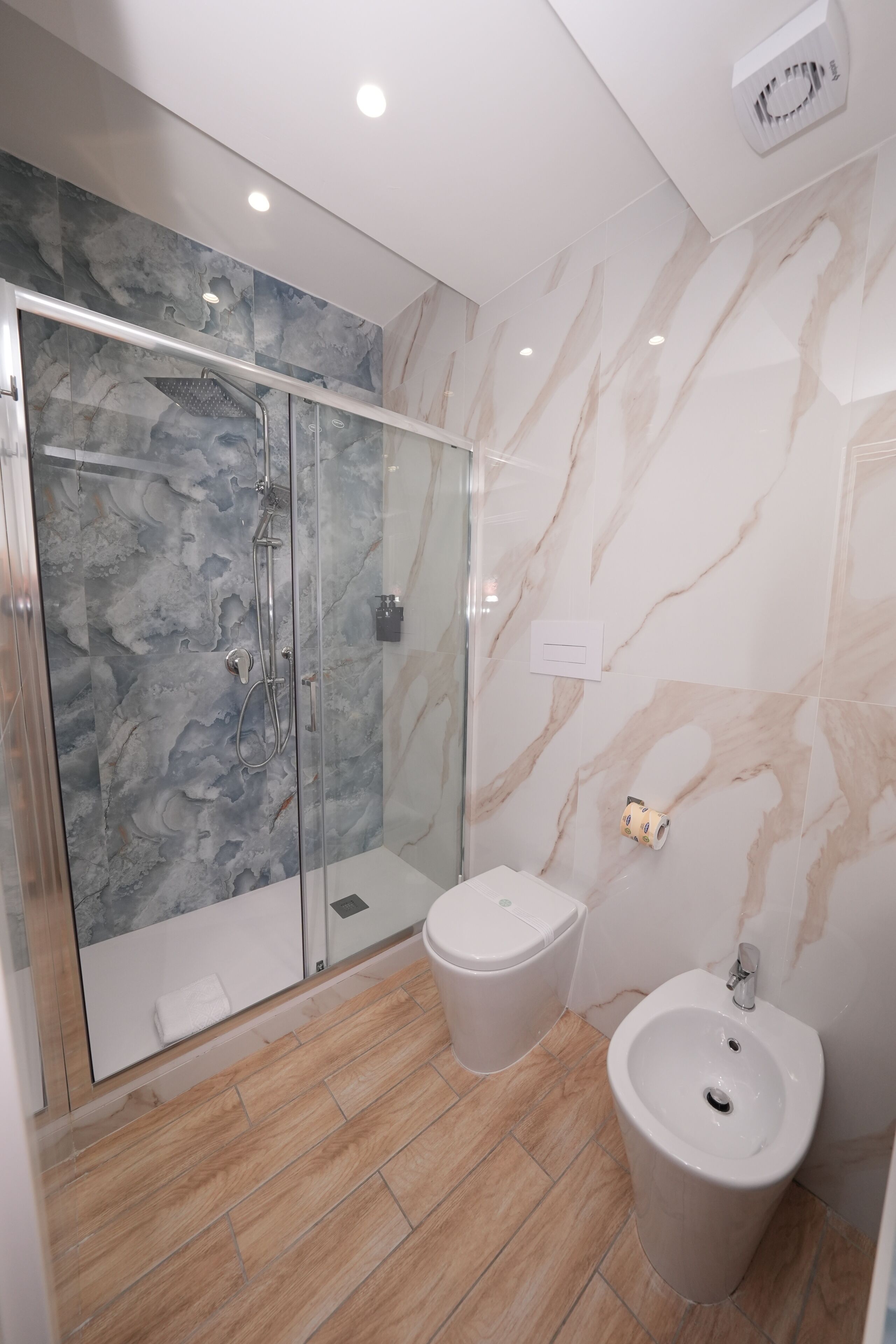 Une salle de bain moderne dotée d’une douche à parois de verre, d’un bidet et de toilettes.