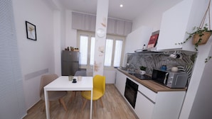 A compact kitchen with a dining table, chairs, a microwave, and a refrigerator. - Partesia  (Naples)
