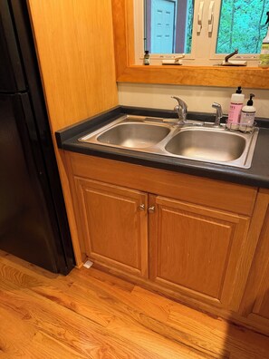 Una cocina con un lavamanos doble, armarios de madera y un refrigerador.
