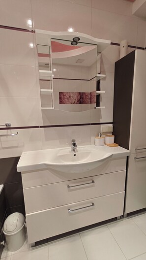 Une salle de bain moderne avec un lavabo blanc, un miroir et des meubles de rangement.