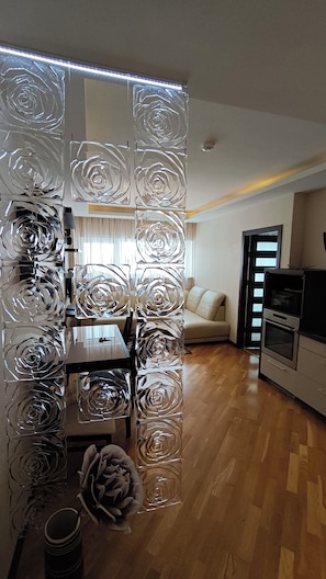Eine moderne Küche mit Holzboden, einer Essecke mit Tisch und Stühlen, einer Couch und einem dekorativen Glastrennwand mit Rosenmuster.