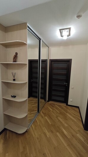 A room with a mirrored wardrobe, a wooden floor, and a door with a handle.