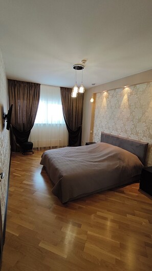 Une chambre à coucher moderne avec un grand lit, une petite table de chevet, une chaise et un luminaire suspendu au plafond.
