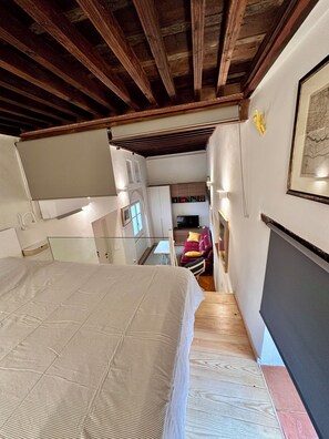Ein Schlafzimmer mit Bett, Treppe, Sofa und Essbereich.
