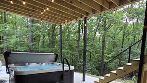 A hot tub under a wooden pergola with steps leading up to a staircase. - The A at Elm Creek - Modern Cabin Retreat ~ Hot tub, Game loft, EV charger (Hot Spring County)