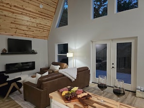 Ein modernes Wohnzimmer mit einer braunen Ledersofa, einem Holztisch mit Käseplatte und einem Weinglas.