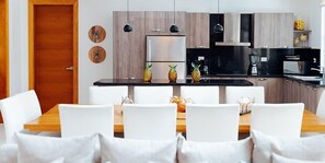 A modern kitchen with a central island, white chairs, and a wooden dining table. - Lifestyle Holidays Vacation Club (Puerto Plata)